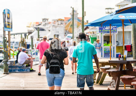Destin, USA - April 24, 2018: City town Harborwalk village boardwalk at marina with couple walking on sunny day in Florida Panhandle, Gulf of Mexico Stock Photo