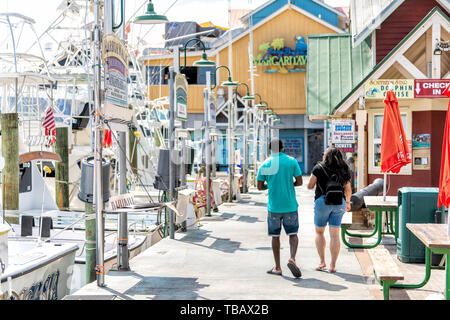 Destin, USA - April 24, 2018: City town Harborwalk village boardwalk at marina with Margaritaville restaurant couple walking on summer day in Florida  Stock Photo