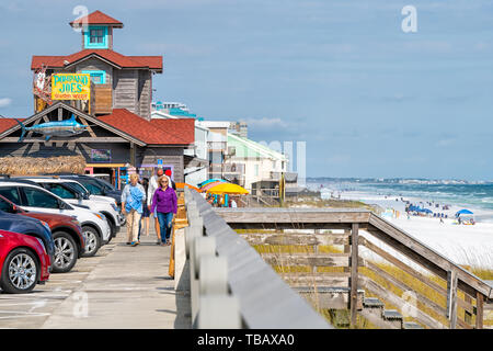 Destin, USA - April 24, 2018: Miramar beach city town village harborwalk or boardwalk, senior people walking by Gulf of Mexico ocean shore with cafe,  Stock Photo