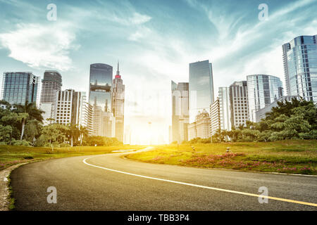 asphalt road and skyscrapers under sunbeam Stock Photo
