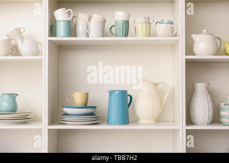 Set of clean dishes on white shelves in kitchen Stock Photo