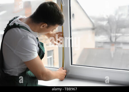 Male worker taking measurements of window in flat Stock Photo