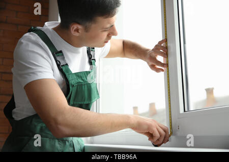 Male worker taking measurements of window in flat Stock Photo