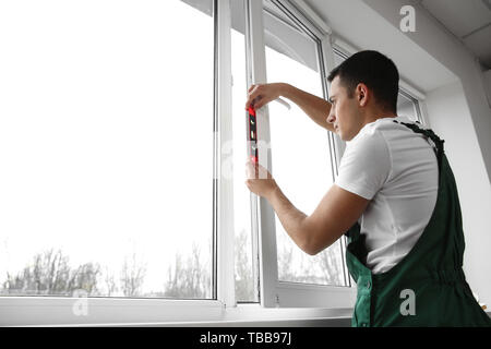 Young worker repairing window in flat Stock Photo