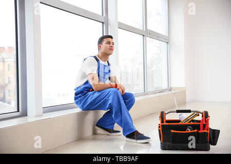 Young worker sitting on window sill in flat Stock Photo