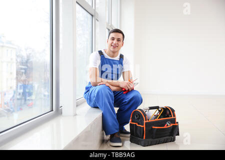 Young worker sitting on window sill in flat Stock Photo