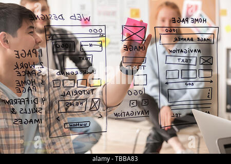 IT designers discussing project, view through transparent board Stock Photo