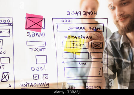 IT designers discussing project, view through transparent board Stock Photo