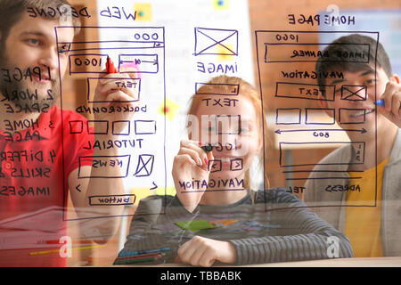 IT designers discussing project, view through transparent board Stock Photo