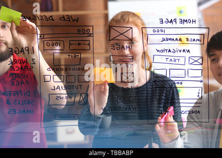 IT designers discussing project, view through transparent board Stock Photo