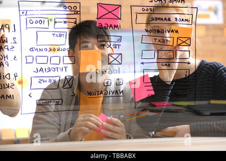 IT designers discussing project, view through transparent board Stock Photo