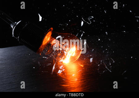 Breaking of light bulb on dark background Stock Photo