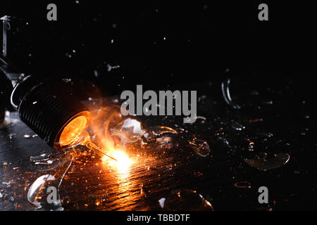 Breaking of light bulb on dark background Stock Photo
