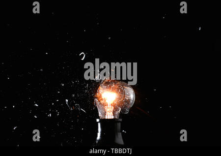 Breaking of light bulb on dark background Stock Photo