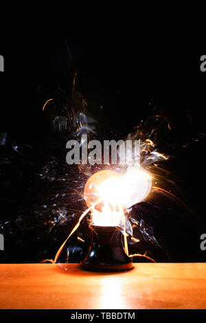 Breaking of light bulb on dark background Stock Photo