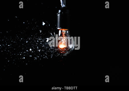Breaking of light bulb on dark background Stock Photo