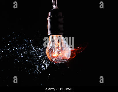 Breaking of light bulb on dark background Stock Photo