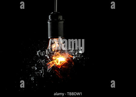 Breaking of light bulb on dark background Stock Photo