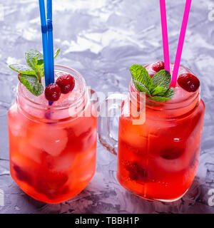 Two cocktail jars of ice-cold homemade lemonade with cranberries, citrus and fresh mint leaves Stock Photo