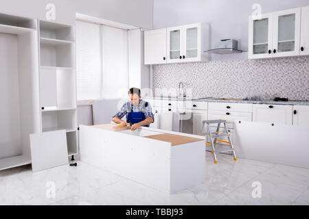Carpenter Repair And Assembling Furniture In The Modular Kitchen Stock Photo