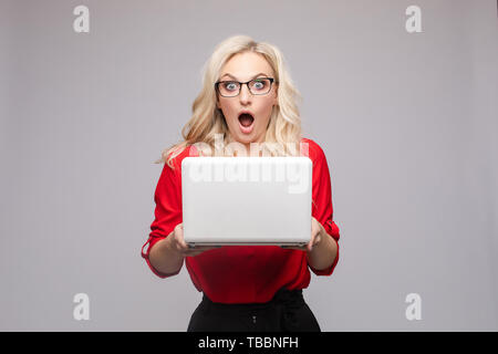 Shocked woman with open mouth keeping computer Stock Photo
