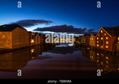 Twilight view of colorful wooden buildings on stilts along the Nidelva River, Trondheim, Norway Stock Photo