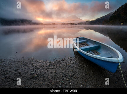 Beautiful mystical sunrise at Lake Shōji with Mount Fuji as a backdrop and a row boat in the foreground Stock Photo