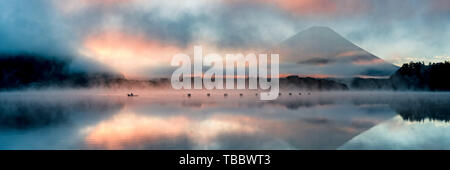 Beautiful mystical sunrise at Lake Shōji with Mount Fuji as a backdrop and a row boat in the foreground Stock Photo