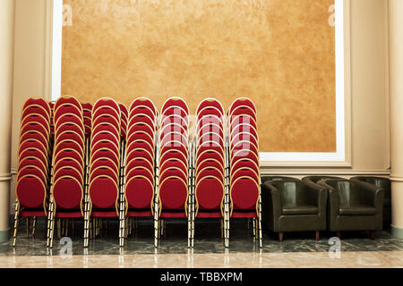 Lots of chairs folded at wall in banquet hall. Stock Photo
