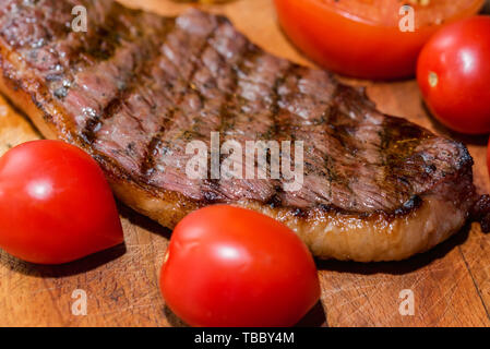 Close up freshly grilled steak on wood with tomatoes Stock Photo