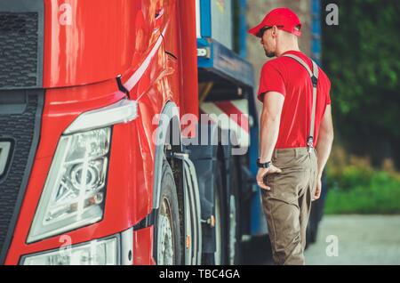 Semi Truck Transportation Concept Photo. Caucasian Trucker in His 30s and Euro Truck with Trailer. Stock Photo