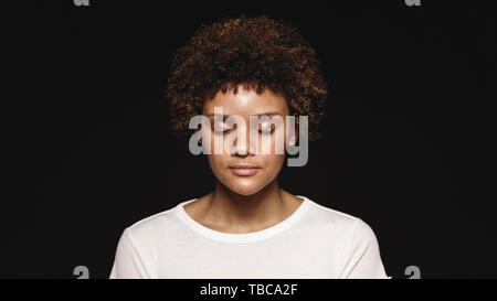 Portrait of a young woman isolated on black background. Curly haired woman with her eyes closed. Stock Photo