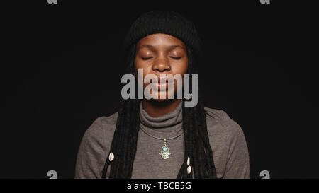 Portrait of african female with closed eyes having long dreadlocks. Portrait of african woman isolated on black background. Stock Photo