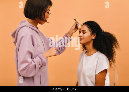 Professional make up artist applying tonal powder on model in studio Stock Photo