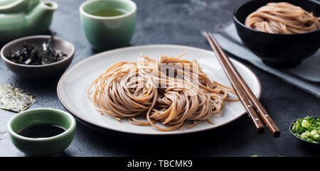 Soba noodles with sauce and green tea set. Japanese food. Black slate background. Stock Photo