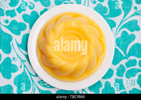 Mango pudding, jelly on white plate Blue textile background. Top view. Copy space. Stock Photo