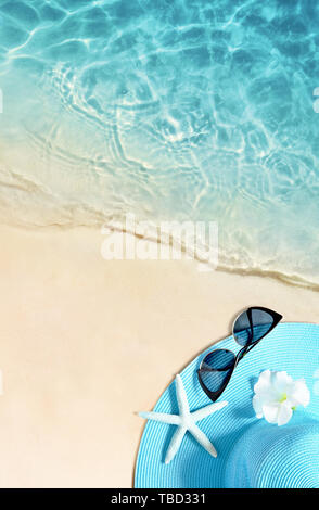 Hat and sunglasses on the sandy beach. Summer background. Stock Photo