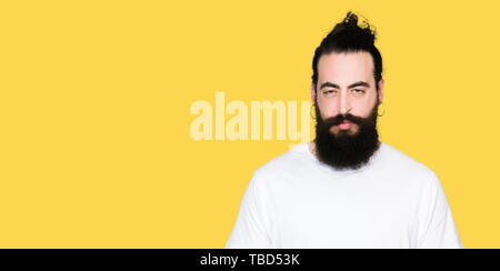 Young hipster man with long hair and beard wearing casual white t-shirt skeptic and nervous, frowning upset because of problem. Negative person. Stock Photo