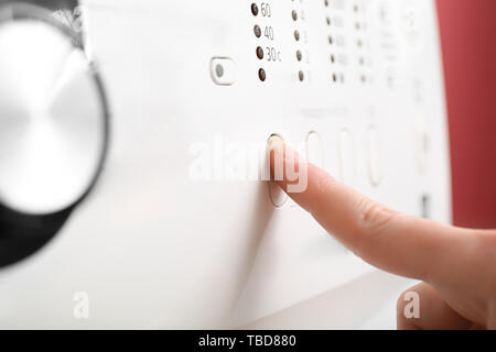Woman adjusting washing machine before doing laundry, closeup Stock Photo