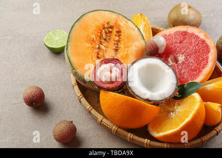 Plate with assortment of tasty exotic fruits on grey table Stock Photo