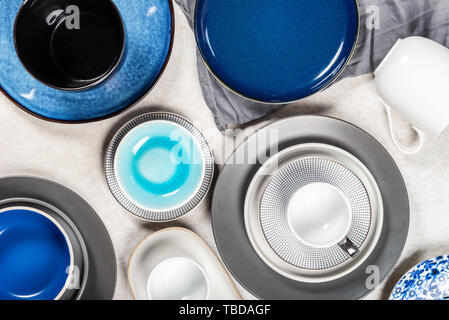 Variety of Empty Blue, Grey and Black Plates with different Mugs on Grey Background, Top View Stock Photo