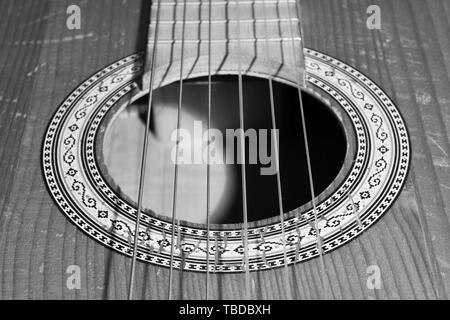 Old guitar body closeup with strings in black and white. Sound hole with decorative rosette. Stock Photo