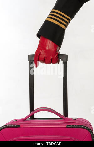 Four gold stripes on a uniform jacket with hands wearing red gloves holding handle of a roller case Stock Photo
