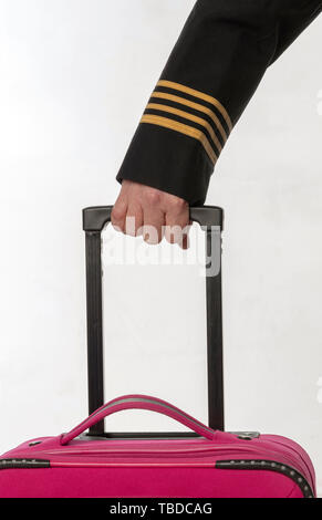 Four gold stripes on a uniform jacket with hands holding the handle of a suitcase Stock Photo