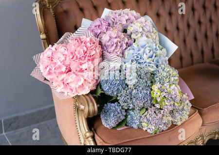Bouquets of hydrangeas lying on vintage sofa. Small Beautiful bouquet of hydrangea flowers. Floral shop concept . Beautiful fresh cut bouquet. Flowers Stock Photo