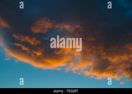 Dramatic evening sky with beautiful clouds illuminated by the setting sun. Stock Photo
