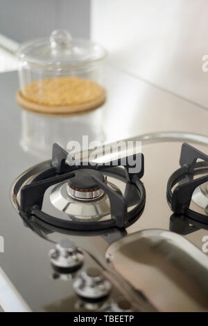 Detail of a gas kitchen in stainless steel, with a transparent container filled with cereal Stock Photo
