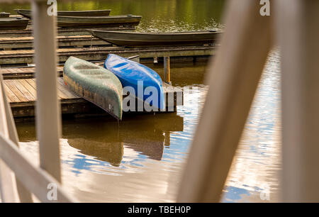 Colorful canoes stored upside down on a dock on a lake with clouds reflected in the water Stock Photo