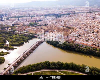 Scenic aerial view of ancient Roman bridge across Guadalquivir river and Moorish architecture of Mezquita-Catedral on background with Cordoba cityscap Stock Photo