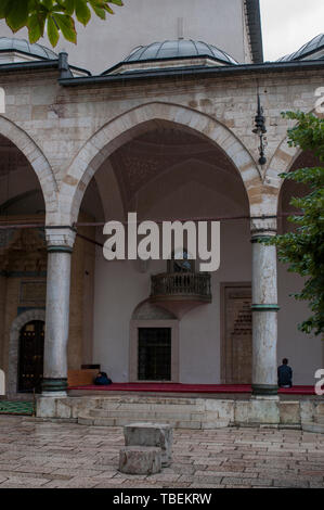 Sarajevo, Bosnia: a muslim man praying in the direction of Mecca outside the Gazi Husrev-beg Mosque (1532) in the old Bascarsija neighborhood Stock Photo